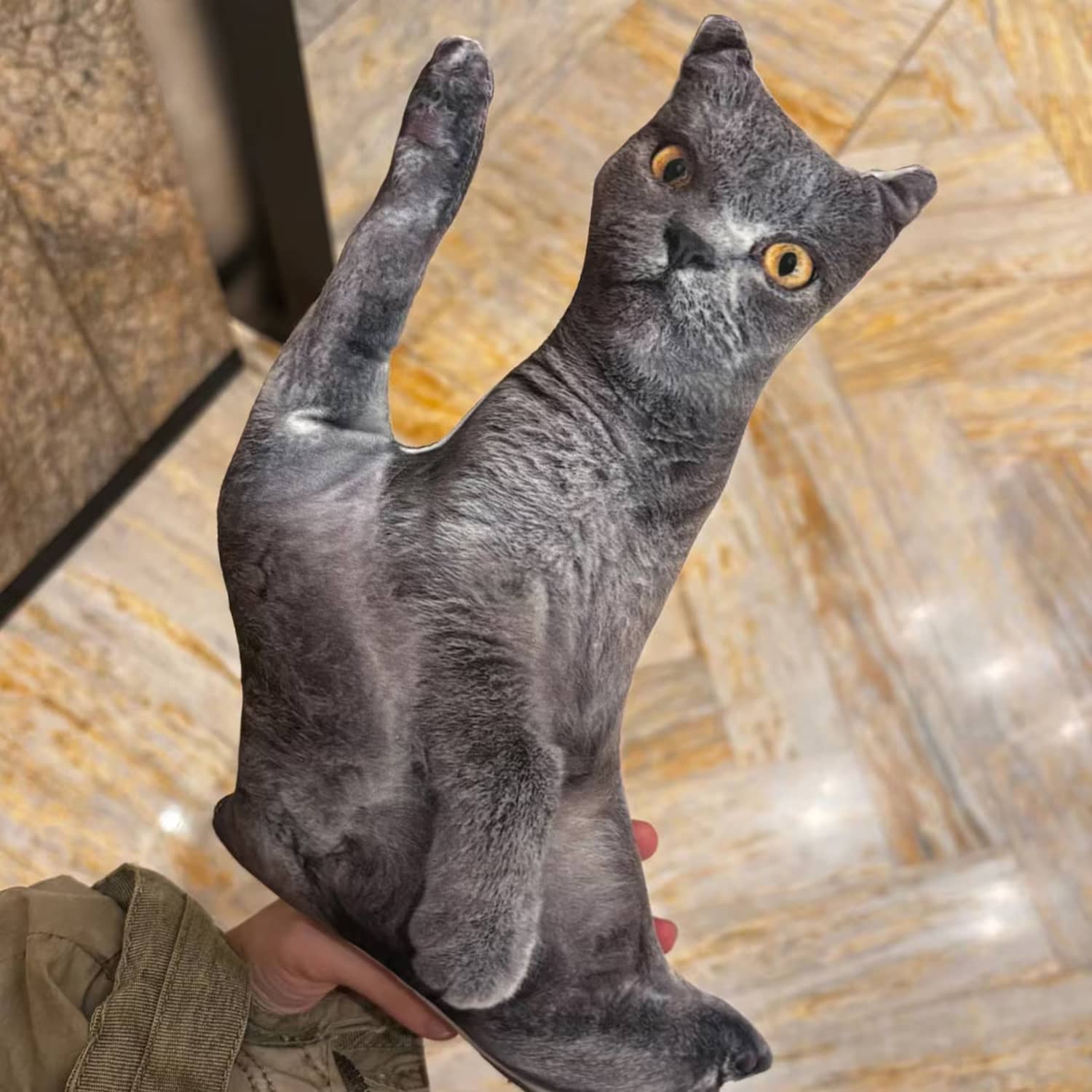 Grey cat shaped custom photo pillow held up by a customer
